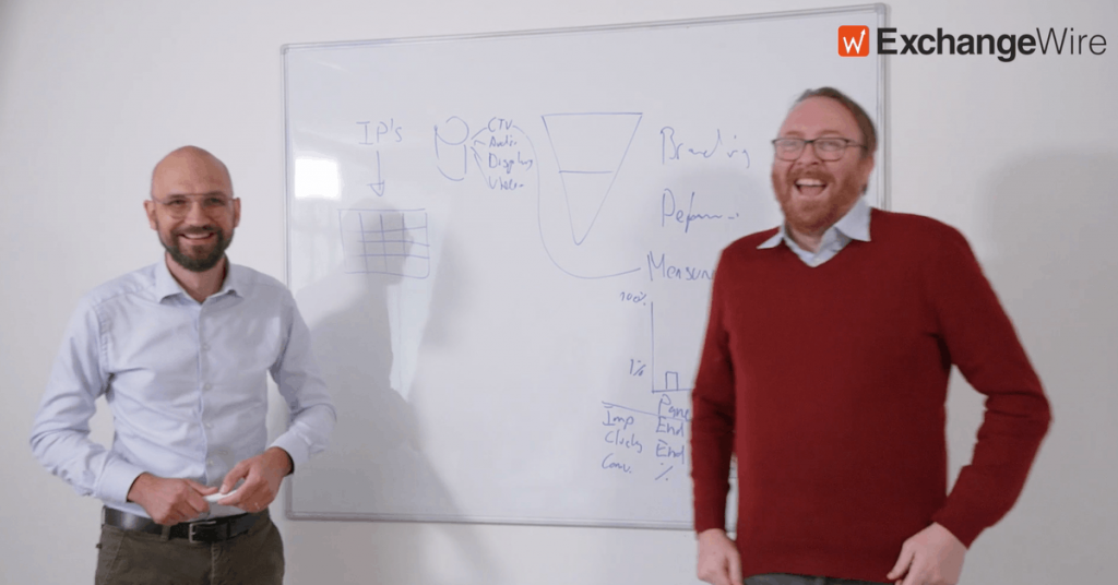 two men smiling in front whiteboard from exchange wire video